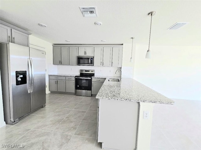 kitchen featuring gray cabinets, appliances with stainless steel finishes, pendant lighting, sink, and light stone counters