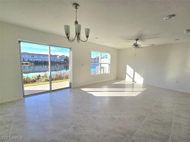 tiled empty room with a water view and ceiling fan with notable chandelier