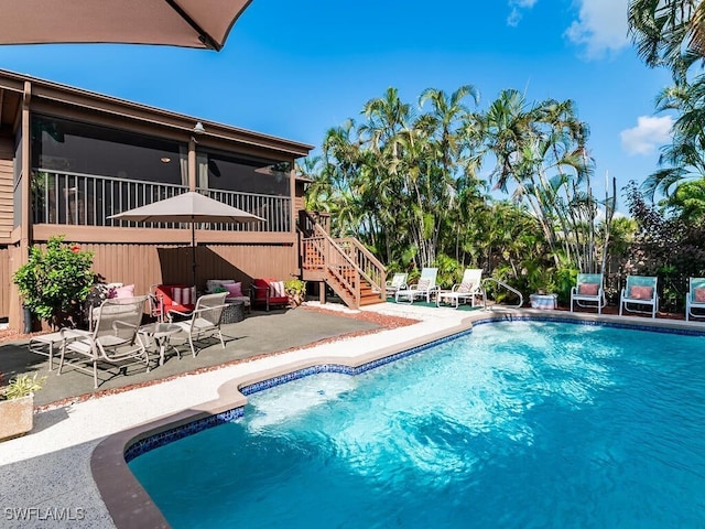 view of swimming pool featuring a sunroom and a patio area