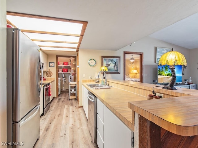 kitchen with white cabinetry, stainless steel appliances, sink, and light hardwood / wood-style flooring