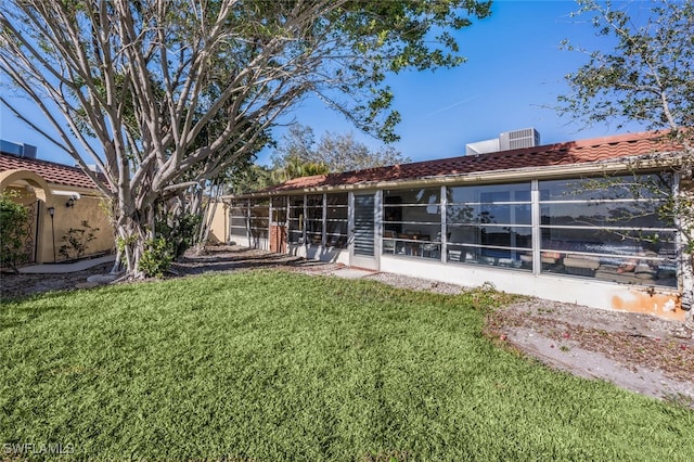 rear view of property featuring a sunroom and a yard