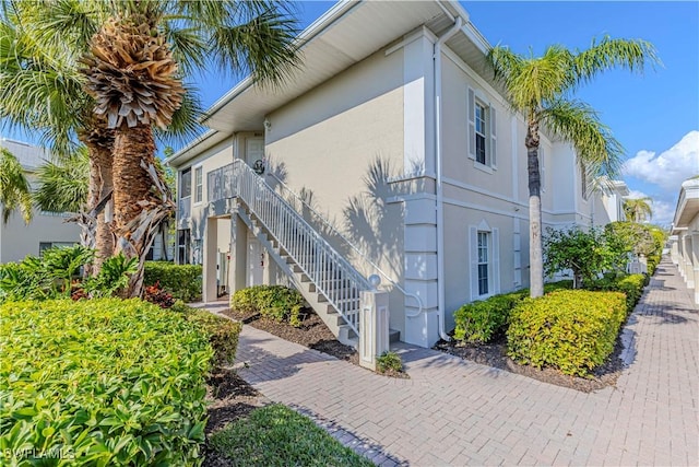 view of side of property featuring stairs and stucco siding