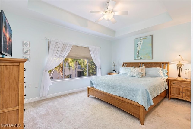 carpeted bedroom featuring a tray ceiling and ceiling fan