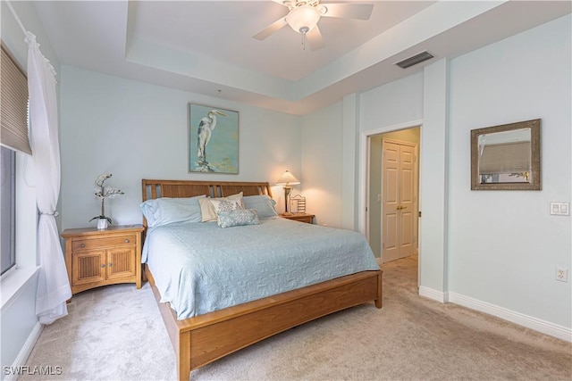 bedroom featuring light colored carpet, ceiling fan, and a tray ceiling