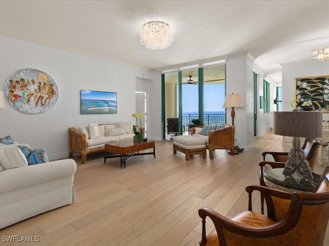 living room with a notable chandelier, ornamental molding, light hardwood / wood-style floors, and floor to ceiling windows