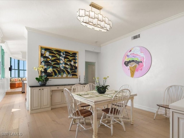 dining area featuring crown molding, a chandelier, and light hardwood / wood-style floors