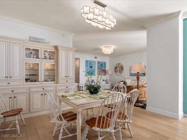 dining room featuring a notable chandelier, crown molding, and light hardwood / wood-style flooring