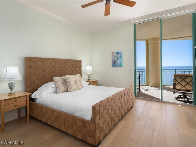 bedroom featuring floor to ceiling windows, a water view, crown molding, wood-type flooring, and access to outside