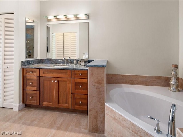 bathroom with vanity, tiled tub, and tile patterned flooring