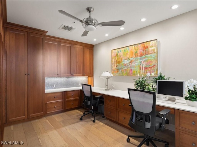 office space featuring built in desk, light hardwood / wood-style flooring, and ceiling fan