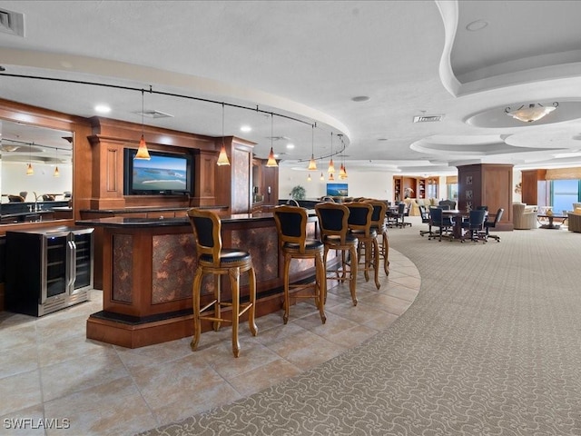 bar with wine cooler and decorative light fixtures