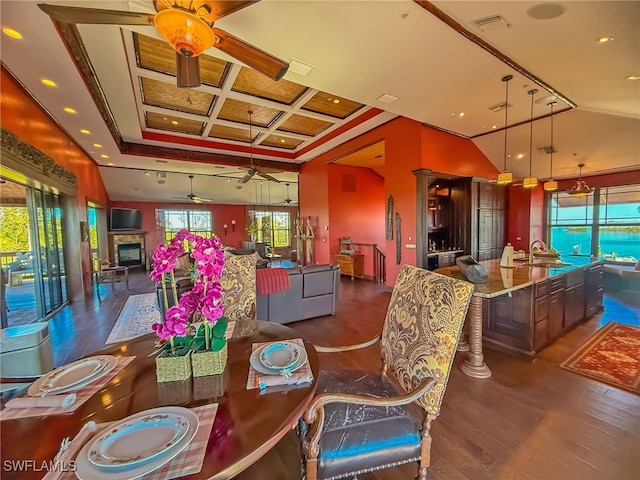 dining area with dark hardwood / wood-style floors, lofted ceiling, sink, coffered ceiling, and ceiling fan