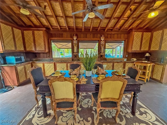 dining space featuring plenty of natural light, ceiling fan, and wood walls