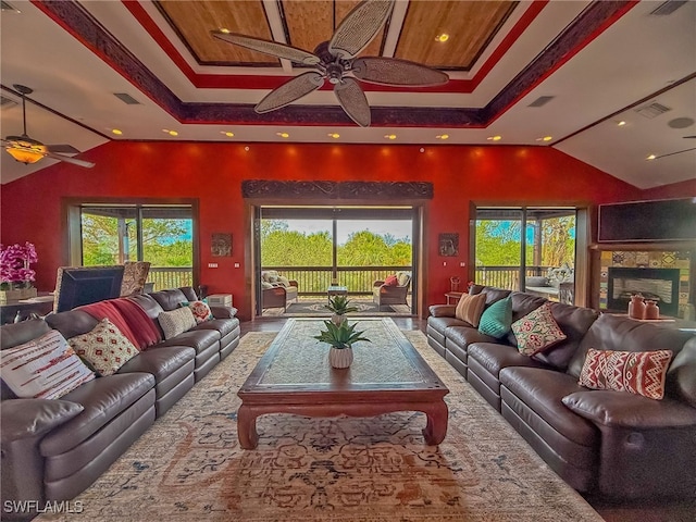 living room with ceiling fan, a tray ceiling, and a wealth of natural light