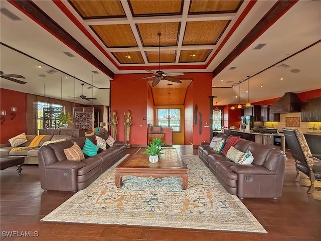 living room featuring a high ceiling, dark hardwood / wood-style flooring, coffered ceiling, and ceiling fan