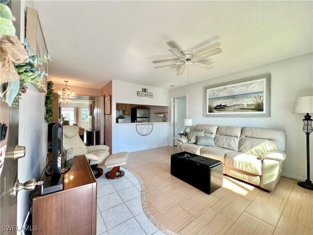 living room with light tile patterned flooring, ceiling fan with notable chandelier, and a textured ceiling