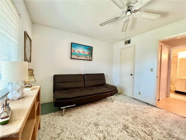 living room featuring ceiling fan and a textured ceiling