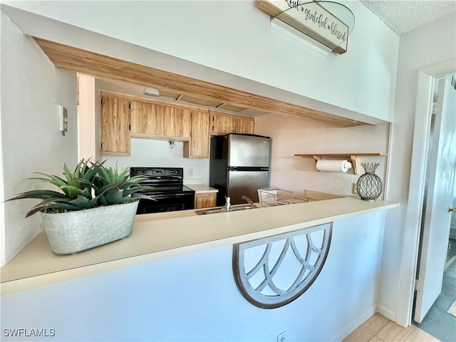 kitchen featuring black electric range oven, sink, and stainless steel refrigerator