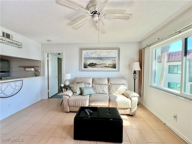 living room featuring ceiling fan and a textured ceiling