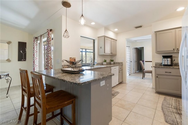 kitchen with light tile patterned flooring, decorative light fixtures, sink, and dark stone countertops