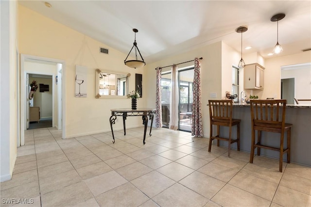 tiled dining space featuring lofted ceiling and sink