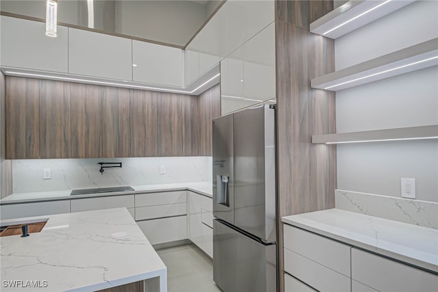 kitchen with white cabinets, light stone counters, and stainless steel fridge with ice dispenser