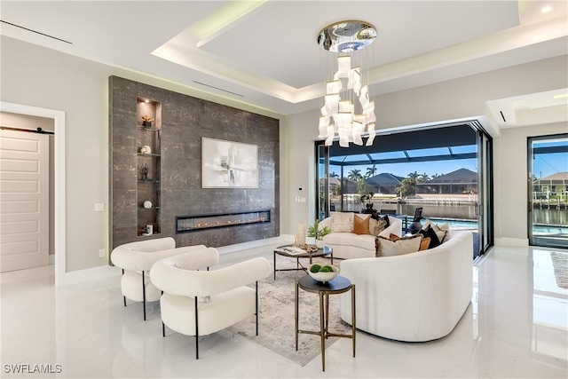 living room with a premium fireplace and a tray ceiling