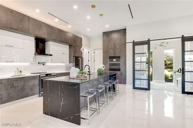 kitchen featuring white cabinetry, appliances with stainless steel finishes, a barn door, and a center island with sink