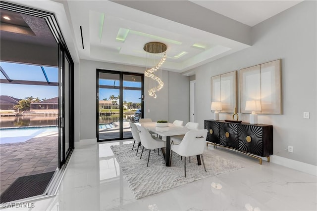 dining space featuring a tray ceiling and a water view