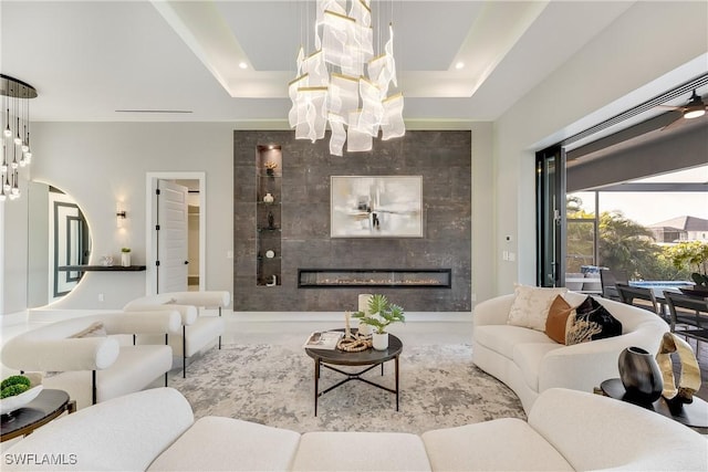 living room featuring a raised ceiling, an inviting chandelier, and a fireplace