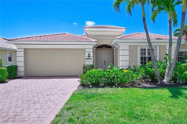 mediterranean / spanish home with a garage and a front lawn