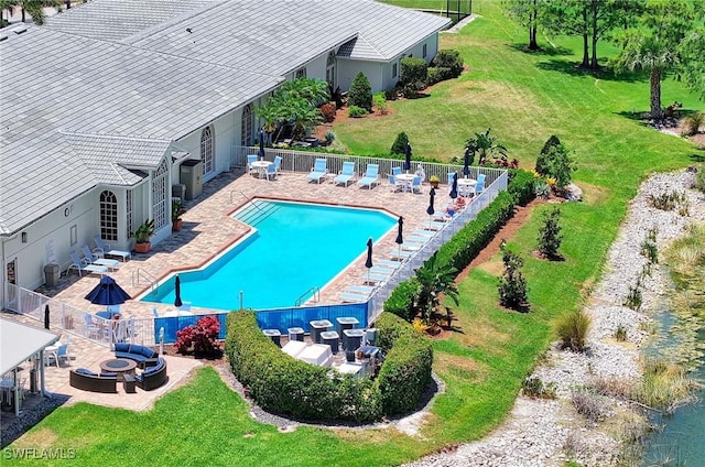 view of swimming pool featuring a patio, a lawn, and a fire pit