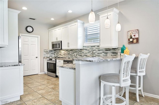 kitchen featuring tasteful backsplash, visible vents, appliances with stainless steel finishes, a peninsula, and white cabinetry