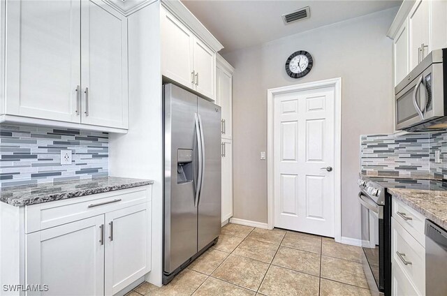 kitchen featuring visible vents, appliances with stainless steel finishes, white cabinetry, light tile patterned flooring, and light stone countertops