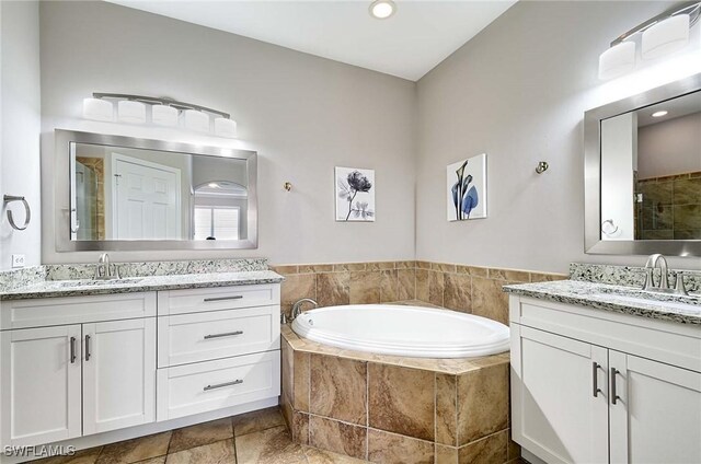 full bath featuring two vanities, a garden tub, a sink, and a shower stall