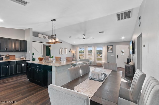 dining room featuring dark hardwood / wood-style floors, ceiling fan, lofted ceiling, and a barn door