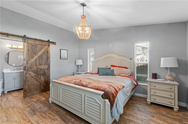 bedroom with sink, connected bathroom, a notable chandelier, dark hardwood / wood-style flooring, and a barn door