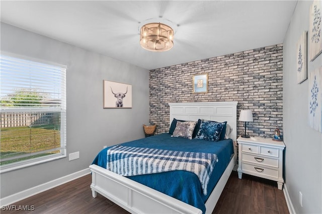 bedroom with brick wall and dark hardwood / wood-style flooring