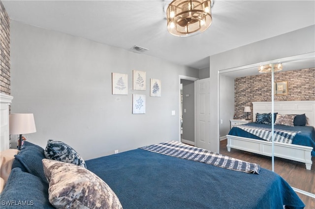 bedroom featuring brick wall and dark wood-type flooring