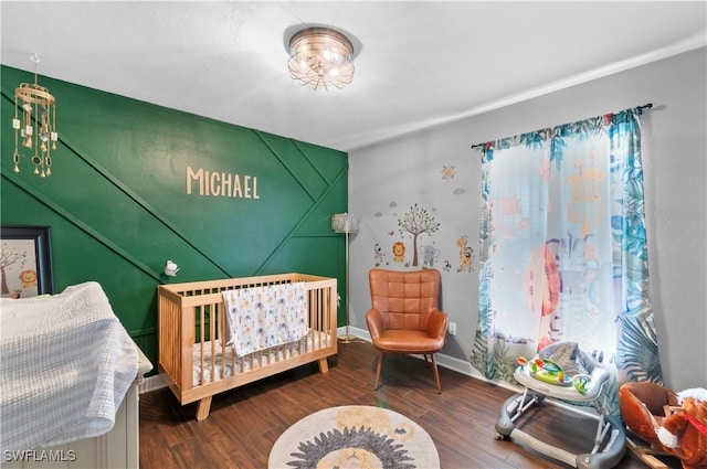 bedroom with a crib and dark hardwood / wood-style floors