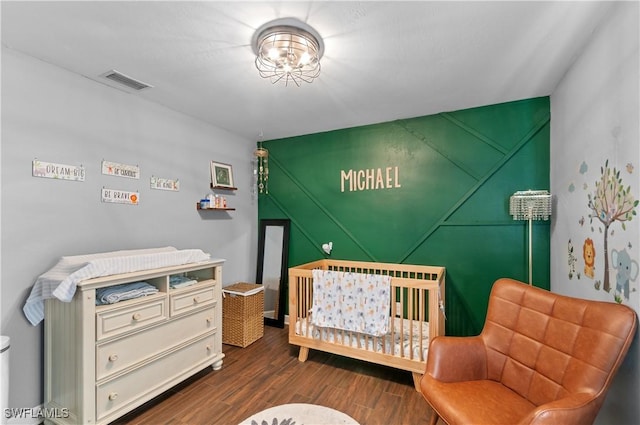 bedroom featuring dark wood-type flooring and a crib