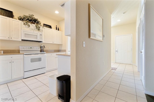 kitchen with light tile patterned floors, white cabinets, and white appliances