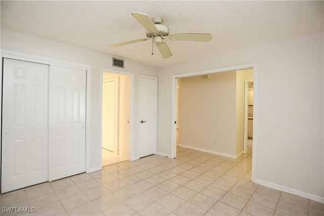 unfurnished bedroom featuring ceiling fan, light tile patterned floors, a closet, and a textured ceiling