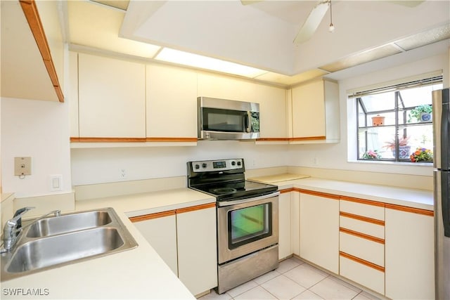 kitchen featuring sink, light tile patterned flooring, white cabinets, and appliances with stainless steel finishes