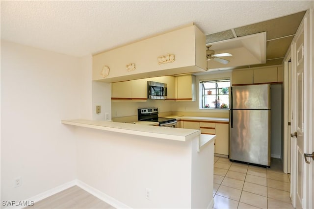 kitchen with ceiling fan, stainless steel appliances, kitchen peninsula, and cream cabinetry