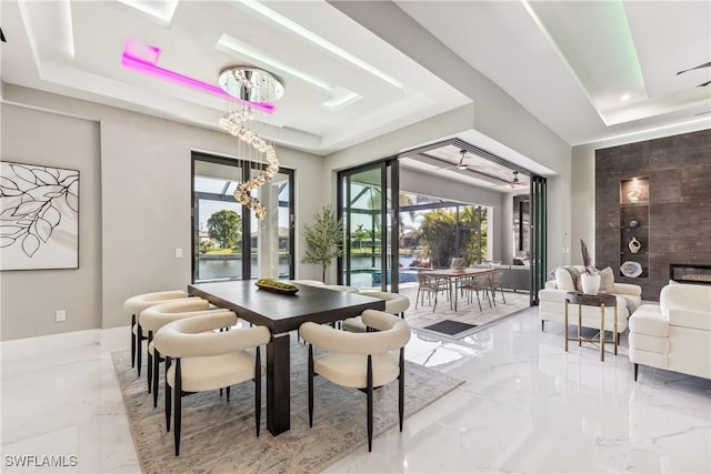 dining room with a raised ceiling and a large fireplace