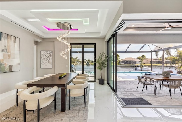 dining area featuring a raised ceiling and a water view