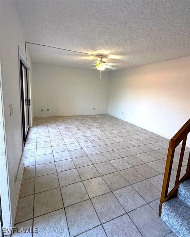 tiled spare room with a textured ceiling and ceiling fan