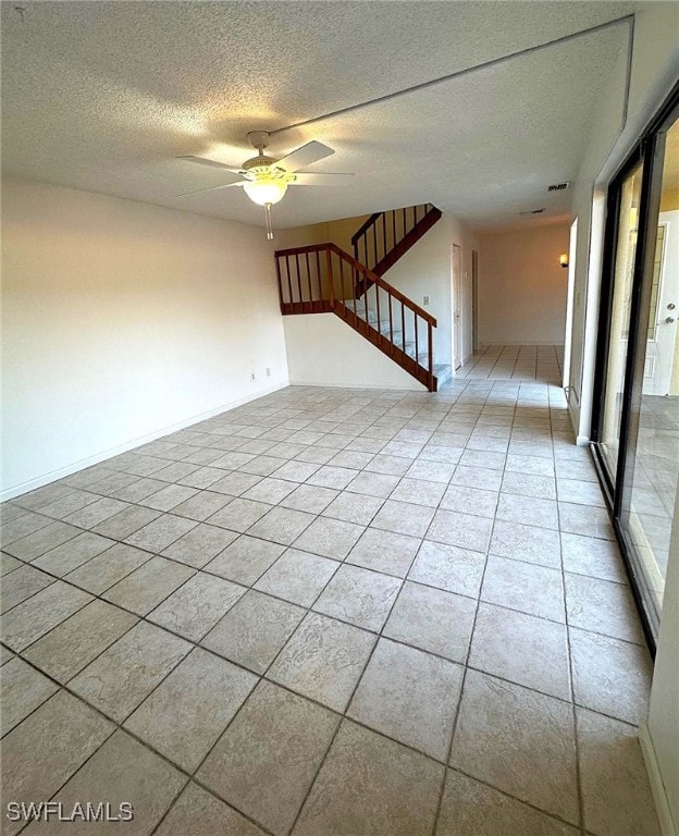 empty room with light tile patterned floors, a textured ceiling, and ceiling fan