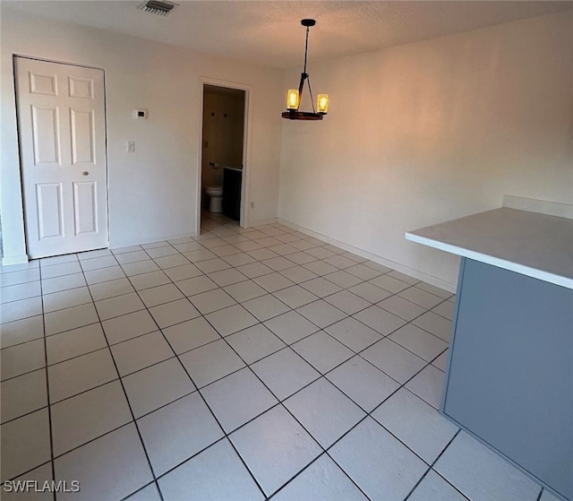 tiled empty room featuring a notable chandelier and a textured ceiling